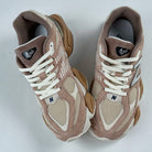Pair of brown and beige sneakers with white laces on a light gray background