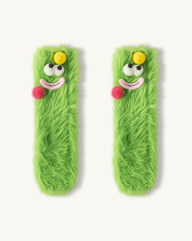 Two green plush toys with cartoon faces on a white background